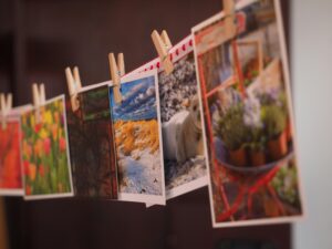 Colorful photographs and postcards clipped with wooden pins in a creative indoor arrangement.